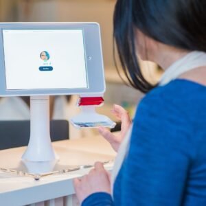 woman in blue long-sleeved shirt in front of turned on monitor